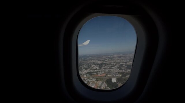 Airplane Wing Seen Through Window Above Expansive City Landscape