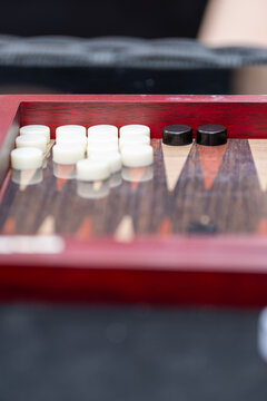Backgammon Board Game Close-Up with White and Black Checkers on Wooden Red Board