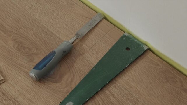 Flooring spacer and chisel tool near installed laminate edge