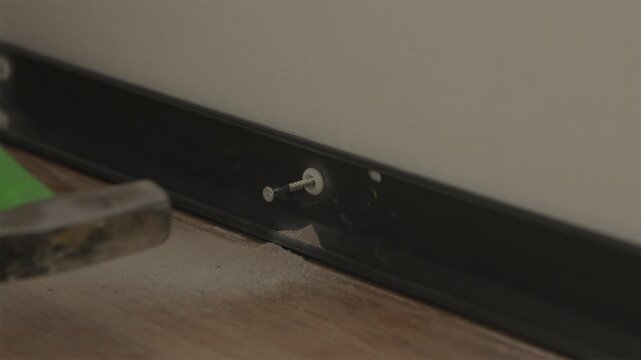 Inserting screw into plastic wall dowel plug in wall