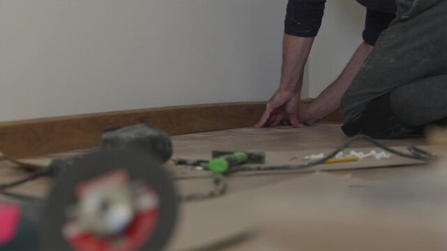 Mounting plastic baseboard skirting along room wall