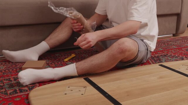 Man assembling wooden table following instruction manual