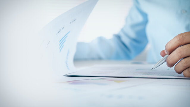 Businessman reviewing business financial reports and charts on desk with copy space, concept of data analysis, accounting, business planning, and corporate performance review.
