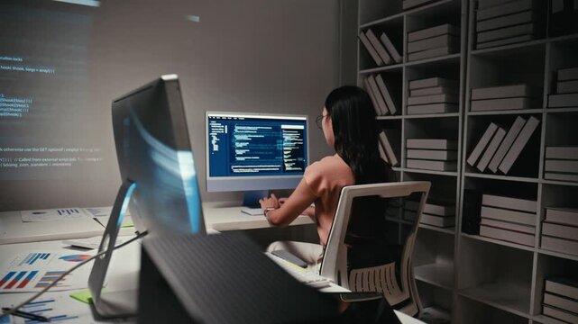 Young asian woman programmer working on a new project, writing code and programming on a computer in a modern office, focusing on software and application development late at night