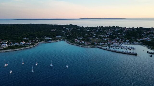 A stunning aerial drone shot capturing the warm golden sunset over the Sotorisce bay and Mulj harbor area on Silba Island, Croatia. The perspective showcases the sheltered marina filled with boats