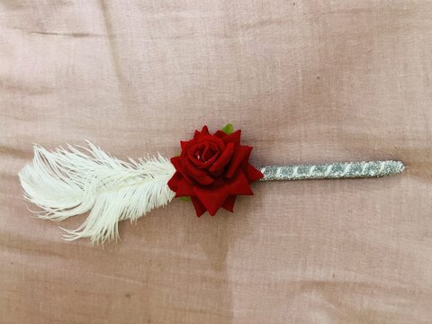 Corsage with a red rose white ribbon and pearl accents on a textured background