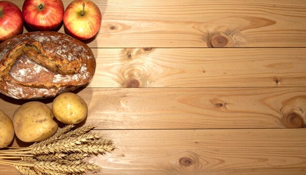 Erntedank Hintergrund mit Bauernbrot, &Auml;pfeln, Kartoffeln und Weizen&auml;hren auf Holztisch