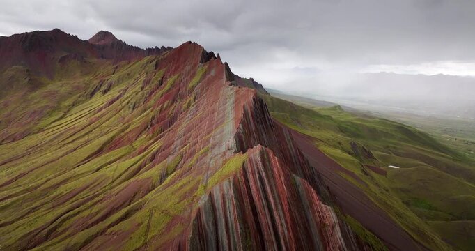 Colourful striped ridge and green Andean slopes of Pallay Punchu Rainbow Mountain near Layo, Canas Province, Cusco, Peru, 4k cinematic drone view
