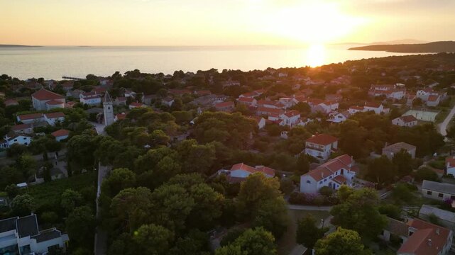 A stunning aerial drone shot capturing the warm golden sunset over the Sotorisce bay and Mulj harbor area on Silba Island, Croatia. The perspective showcases the sheltered marina filled with boats
