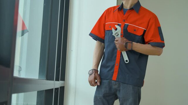 Professional construction worker holding a large adjustable wrench in a modern building interior