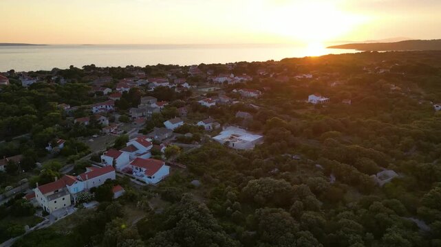 A stunning aerial drone shot capturing the warm golden sunset over the Sotorisce bay and Mulj harbor area on Silba Island, Croatia. The perspective showcases the sheltered marina filled with boats