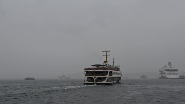 Rear view of a classic passenger ferry leaving a foggy Istanbul port with a wake behind it while a large white cruise ship is docked at the pier and small boats fade into the gray mist