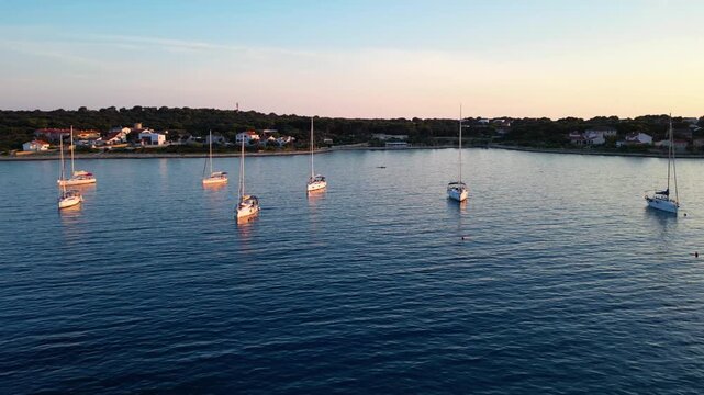A stunning aerial drone shot capturing the warm golden sunset over the Sotorisce bay and Mulj harbor area on Silba Island, Croatia. The perspective showcases the sheltered marina filled with boats
