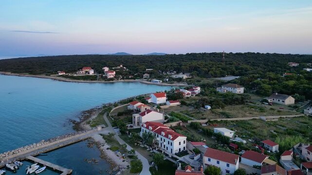 A stunning aerial drone shot capturing the warm golden sunset over the Sotorisce bay and Mulj harbor area on Silba Island, Croatia. The perspective showcases the sheltered marina filled with boats