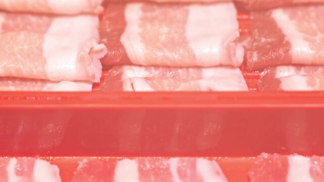 Raw Pork Belly Slices Arranged in Rows on Red Tray with Visible Fat Marbling
