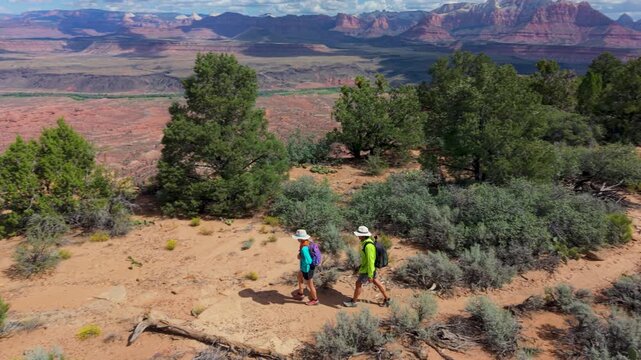 Aerial view of senior couple hiking on Gooseberry Mesa in Utah, enjoying stunning views of Zion National Park and the surrounding landscape.
