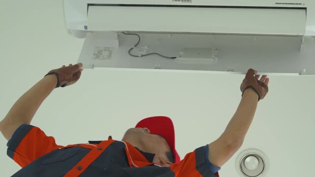 Professional technician performing maintenance on a wall mounted air conditioning unit indoors