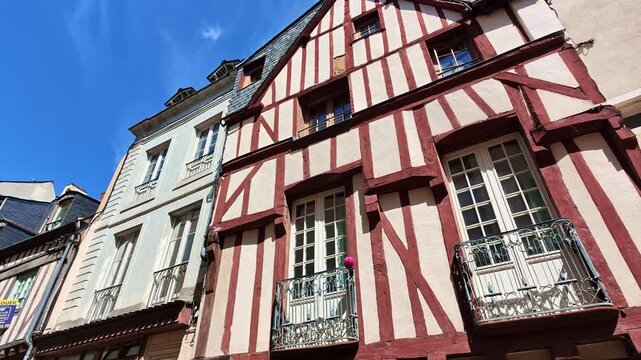 Laval Grande Rue historic timber framed house with exposed structural beams, projecting upper floors, ornate balconies and slate roof beside traditional stone architecture, camera pan