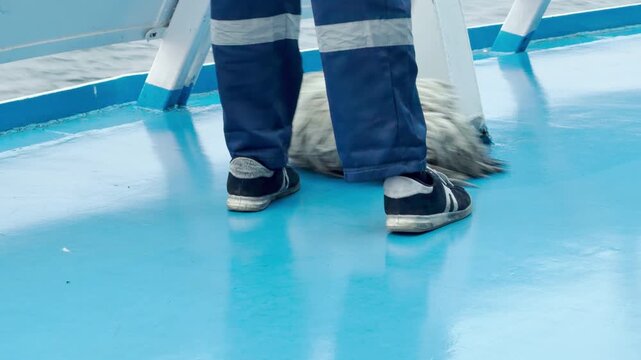 A worker mops a bright blue deck on a cruise ship. The careful routine creates a calm atmosphere on Lake Ladoga. Every sweep brings a feeling of fresh order.