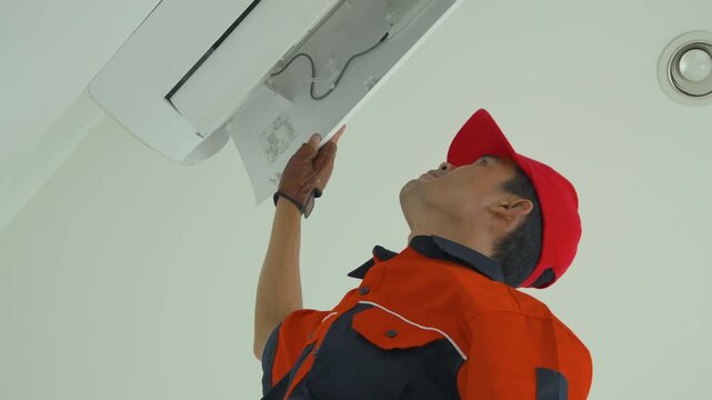 Professional technician in uniform performing maintenance on a wall mounted air conditioner unit