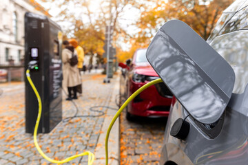 Fototapeta na wymiar Electric car charges at station, highlighting shift from oil dependence toward clean mobility. EV charging symbolizes energy crisis, fuel scarcity, sustainability, electrification, and transition