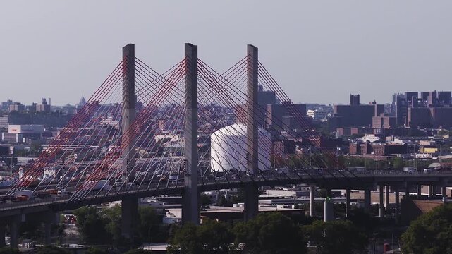 Aerial view tracks vehicular traffic moving across the Kosciuszko Bridge over Newtown Creek, connecting Brooklyn and Queens in New York City on a bright day.