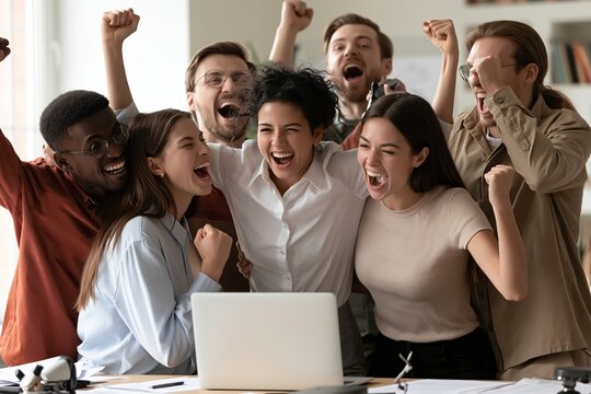 Excited diverse business team cheering with raised hands in front of a laptop