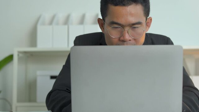 Professional man in a suit working on a laptop computer at a clean modern office desk space