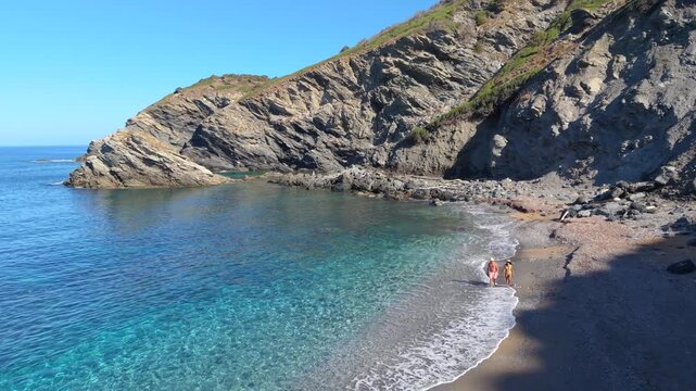 A couple experience the serene atmosphere of La Frana Beach, nestled in Sardinia, Italy. Crystal-clear waters and stunning cliffs create a picturesque escape perfect for relaxation and exploration.