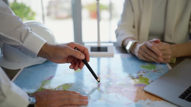 Business professionals analyzing world map and discussing international strategy, identifying target markets and planning global operations, expansion opportunities and long-term corporate development