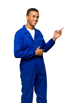 Young Smiling African American Mechanic in Blue Overalls Pointing to the Side Isolated on White Background