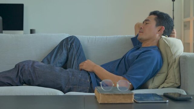 A contemplative man resting on a comfortable sofa in a bright and modern living room interior