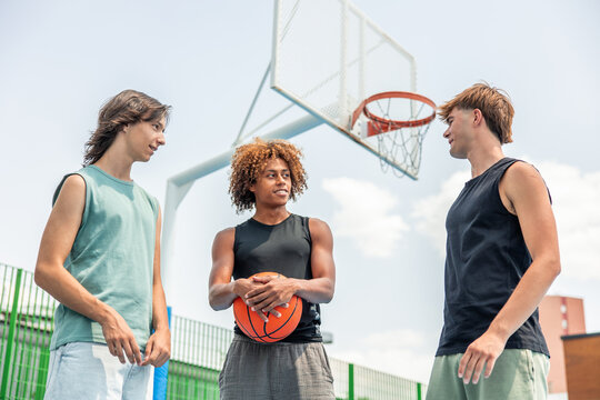 Multicultural friends talking on outdoor basketball court