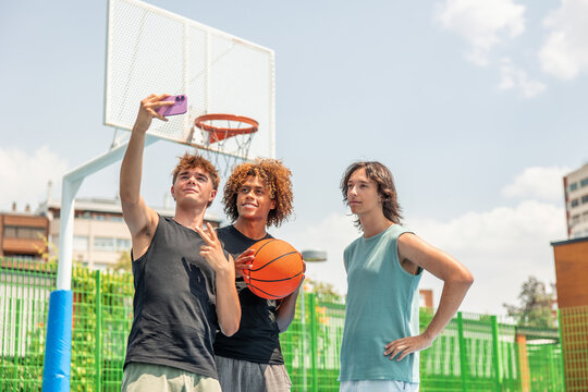 Diverse teenage friends taking selfie on basketball court