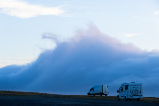 Camper vans parked on mountain with rolling clouds at sunrise