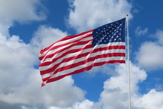 Fluttering American flag against blue sky and clouds