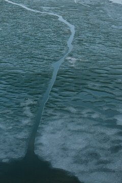Abstract texture of a deep crack opening in a frozen lake ice surface