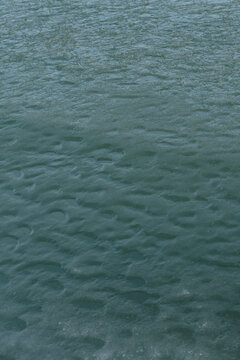 Abstract texture of repetitive water ripples on a dark pond surface