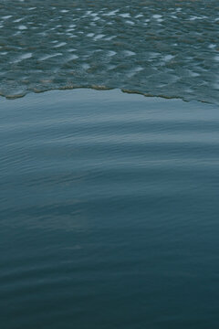 Minimalist background of smooth deep blue water transitioning into small ripples