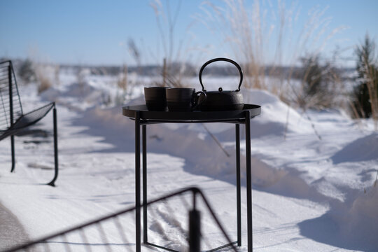 Cozy winter terrace with a black tea table set against a snowy landscape