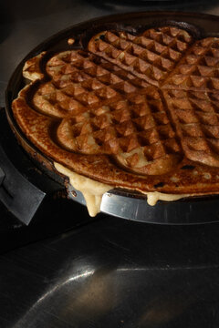 Baking fresh homemade heart shaped waffles in a waffle maker iron