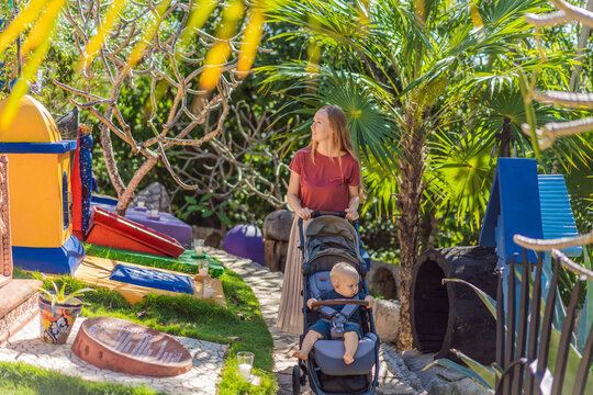 Woman pushing baby stroller through traditional Mexican cemetery during Day of the Dead, exploring colorful cultural heritage with her infant in Mexico