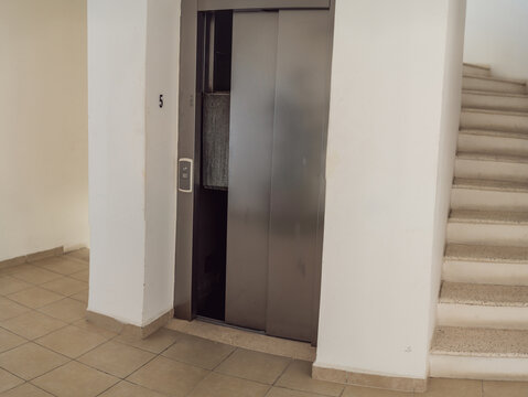 Elevator stuck between floors with doors open, showing lift malfunction, building safety issue, urban infrastructure problem and emergency risk concept
