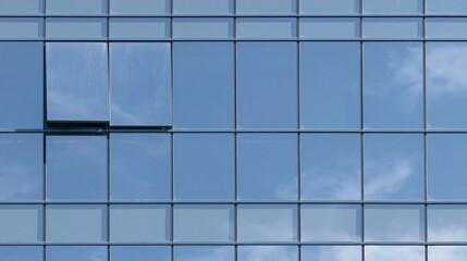Fototapeta premium Close-up of a modern glass curtain wall reflecting blue sky and clouds