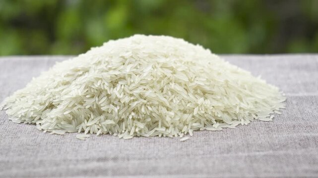 Static shot of basmati rice pile with waving leaves background, 4K