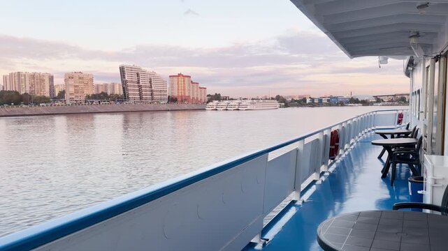 A cruise ship deck glides gently along the Neva River, Saint Petersburg. The calm water reflects a soft evening sky. The quiet view brings a peaceful and serene feeling.