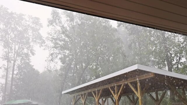 Rain pours down heavily on wooden shed near forest sky is dark cloudy during thunder storm
