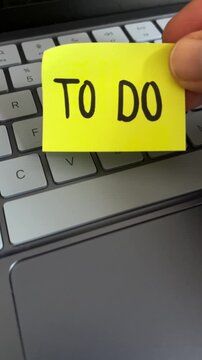 Hand holding to do list sticky note over laptop keyboard