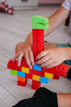 Child's hands assembling a toy from plastic blocks.