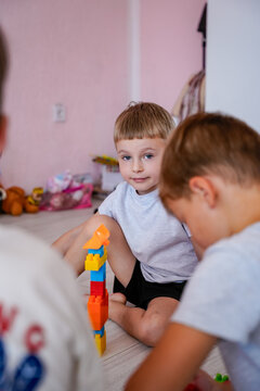 Portrait of a little boy playing with constructor blocks on the floor.